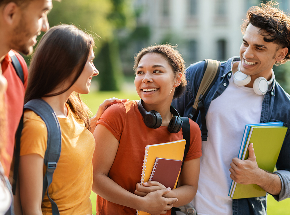 Students holding books interacting with each other.