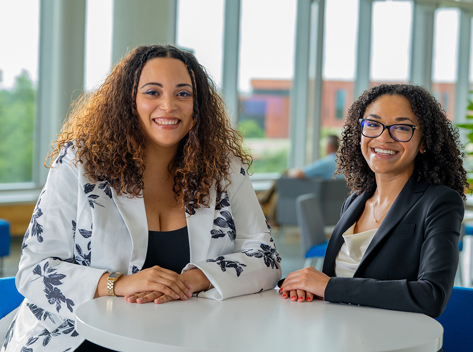 Two graduates in the UHD welcome center to talk to future students on UHD