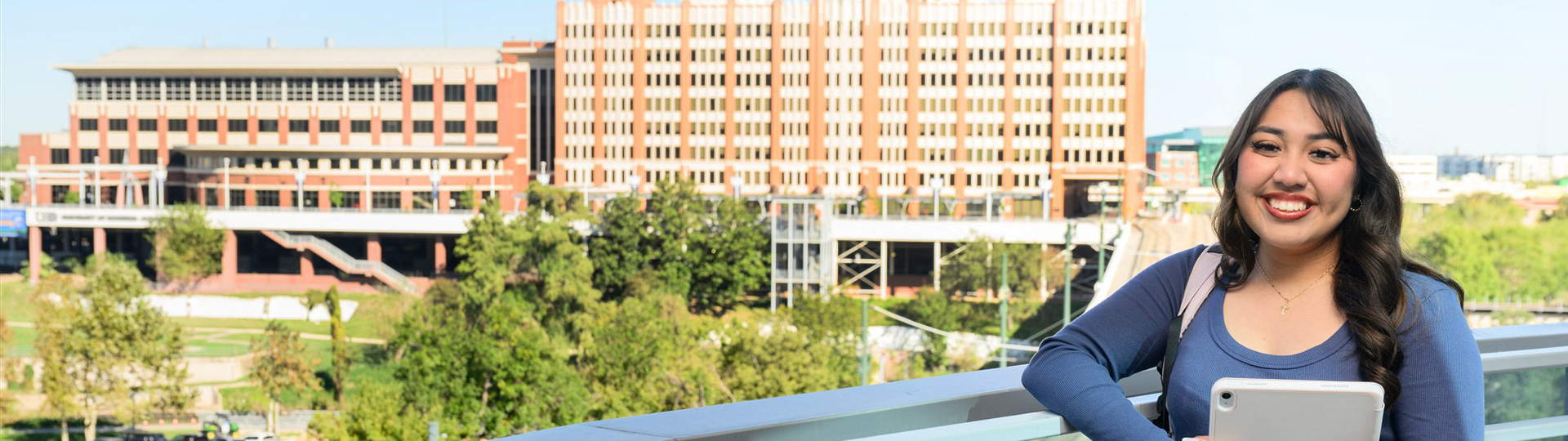Smiling UHD female student with the One Main Building and Academic Buuilding in the background