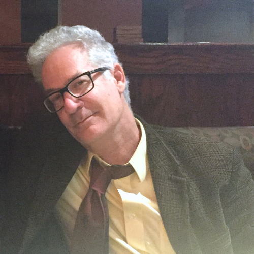 Dr. Henry Foust wearing a yellow shirt, burgundy tie, and brown jacket.