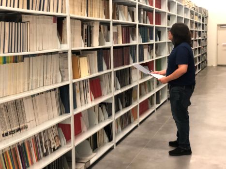 Abraham Leija standing in front of a shelf of archive materials