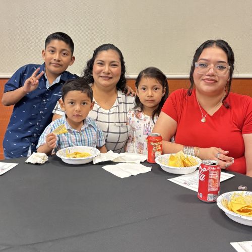 A family of three children and two adults at a table eating.