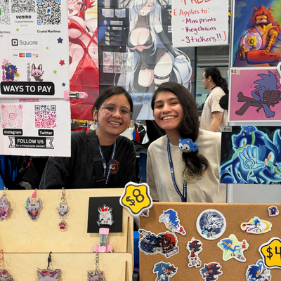two vendors smile at a booth with stickers at gatorcon
