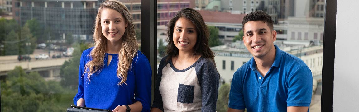 Three students siting in front of a window that is looking at downtown Houston Bayou's Best