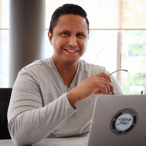 Jhonathan David Shaikh UHD alum smiles while seated at a computer 