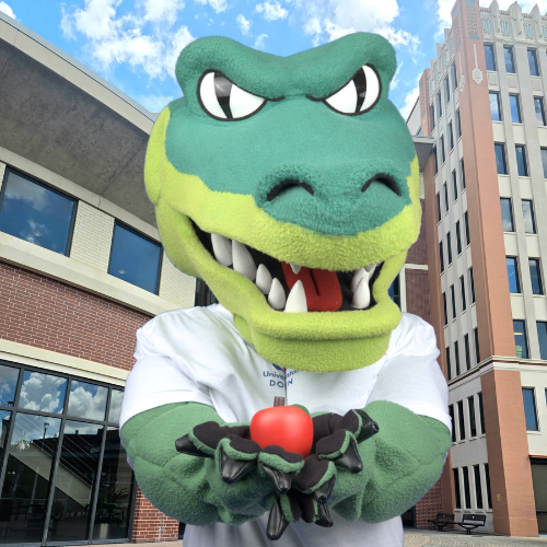 University of Houston Downtown mascot Ed-U-Gator holds an apple on the south deck 