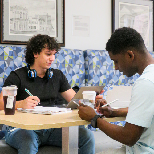 two university of houston downtown students work on laptops and tablets in the W.I. Dykes Library 