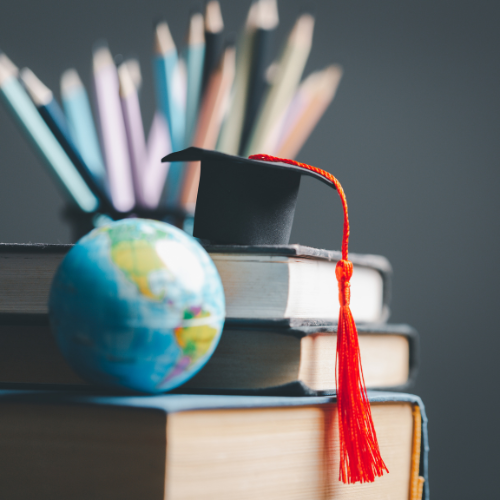 A globe and graduation cap sit atop a stack of books