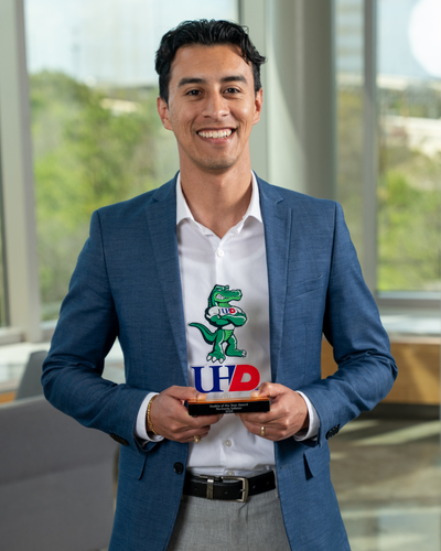 Norberto Salazar smiles while holding the University of Houston Downtown's 2024 Rookie of The Year Award 