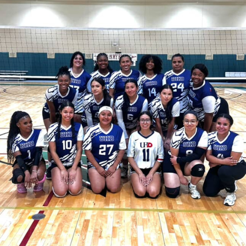 Students on University of Houston Downtown's Women's Volleyball team smile on a court 
