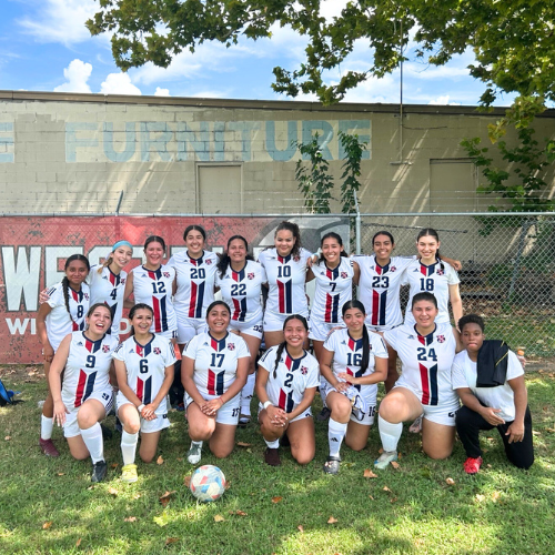 UHD women's soccer team smiles outside