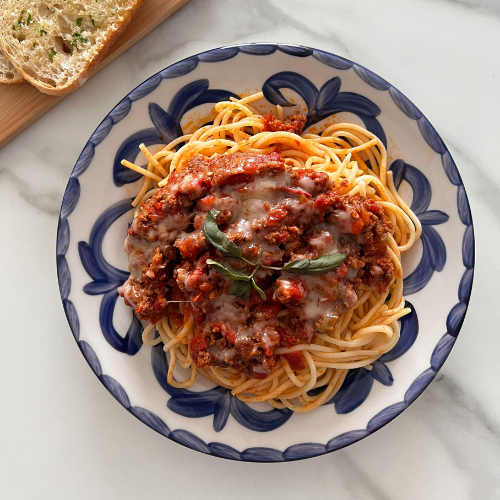 Plate of spaghetti with meat sauce and a cutting board with garlic toast. 