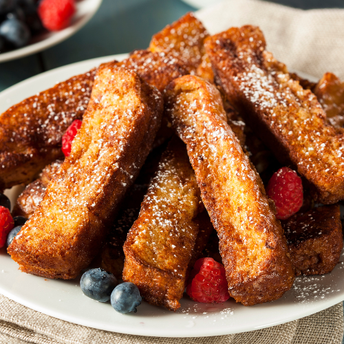 A plate of french toast sticks with blueberries and raspberries